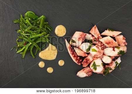 Octopus Arm Slices And Seaweed Salad On Black