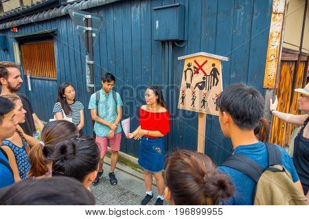 KYOTO, JAPAN - JULY 05, 2017: Crowd of people listening at tourist girl the advice and recomendations to visit in the city on Gion district in Ky, Japan.