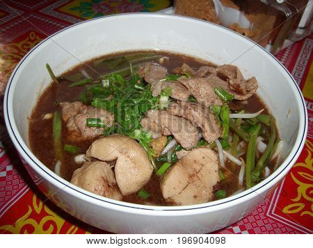 Chicken and pork stew with kangkung leaves in savory sauce served in a white round bowl, a favorite dish in the Philippines