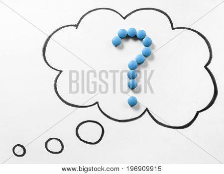 Wondering medical issues or no idea about correct medication or drug. Question mark from pills in thinking speech bubble and thought cloud hand drawn on paper with marker.