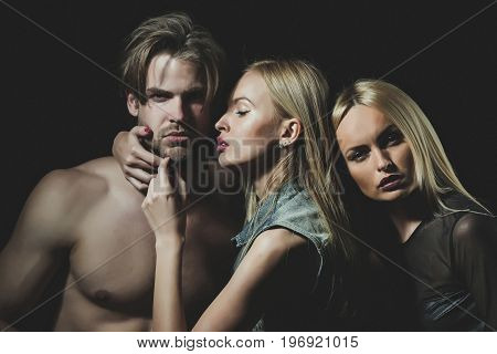 Relations of girls and guy. twins with sexy man. Love and romance. Man with muscular body with sexy women. Boyfriend and girlfriend on black