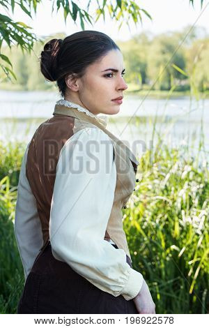 Woman in vintage clothes on the river bank