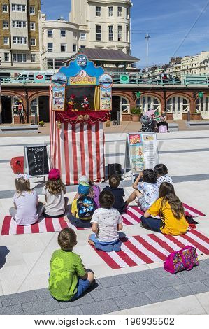 BRIGHTON UK - MAY 31ST 2017: A group of children watching a traditional Punch and Judy puppet show on the seafront in Brighton UK on 31st May 2017.