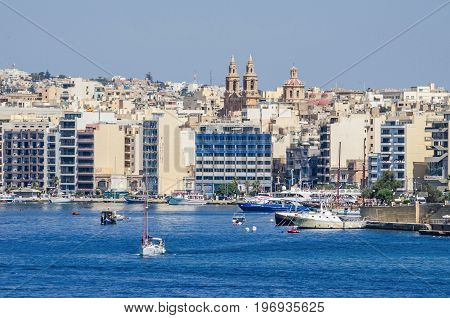 Sliema Malta - June 4 2017: Sliema Waterfront densely covered with modern buildings Sacro Cuor Parish Church and sailing boats as seen from Valletta.