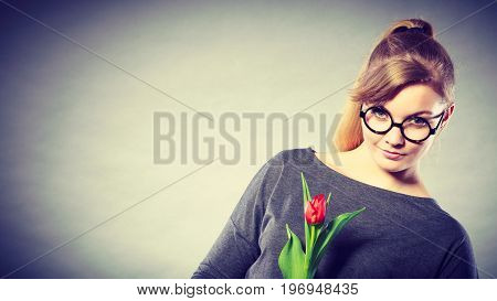 Delicacy and subtlety of women. Young adorable woman with spring flower. Portrait of beauty delicate girl in glasses with red beautiful tulip.
