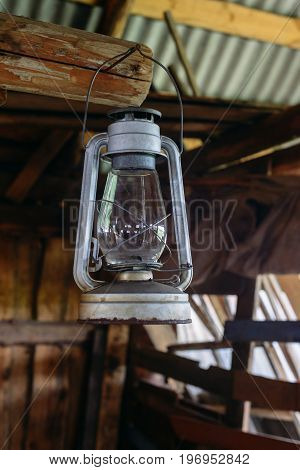 The old rusty kerosene lamp hangs on the nail in a half-ruined wooden building