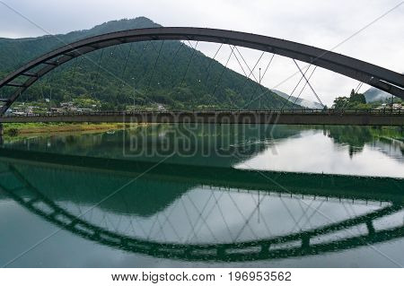 Arch Bridge Over Kiso River With Mountains On The Background