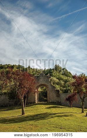 Bomarzo, Italy - May 20, 2013. View of stone wall and gate at sunset amidst the vegetation in the Park of Bomarzo, also known as Park of Monsters, near Viterbo. Located in the Lazio region, central Italy
