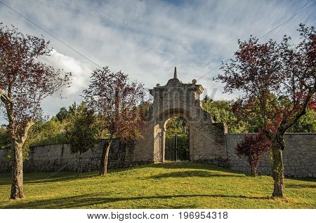 Bomarzo, Italy - May 20, 2013. View of stone wall and gate at sunset amidst the vegetation in the Park of Bomarzo, also known as Park of Monsters, near Viterbo. Located in the Lazio region, central Italy