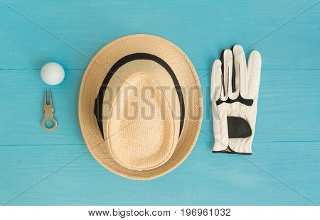 Golf concept : panama hat glove golf balls divot repair tool on wooden table. Flat lay with copy space.