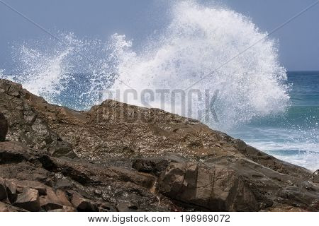 a wave is splashing against a rock close to the shore of the spanish island fuerteventura