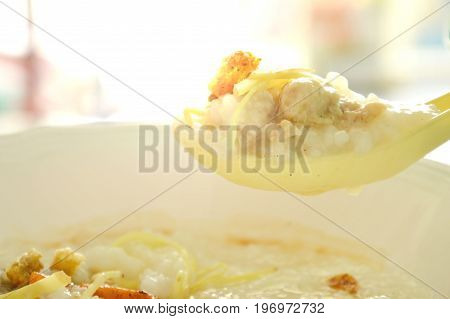 rice porridge with minced pork and slice ginger on plastic soup spoon