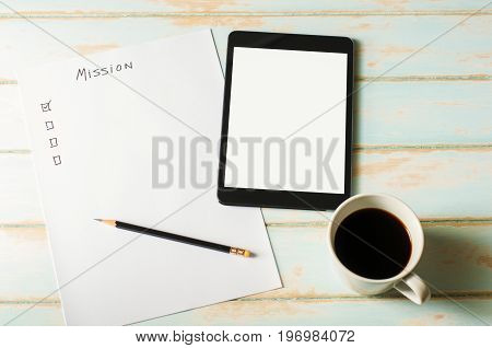 Digital tablet on skyblue color desk with blank white screen. Check list on paper for planning work. Check list Sheet for mission.