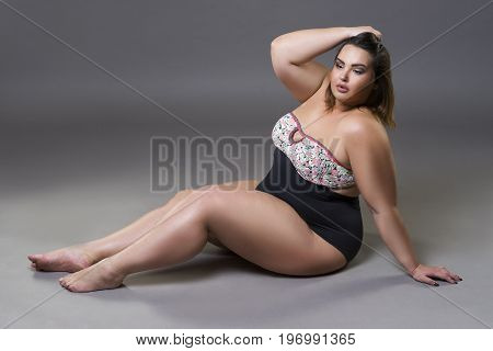 Plus size fashion model in sexy swimsuit young fat woman on gray studio background overweight female body full length portrait