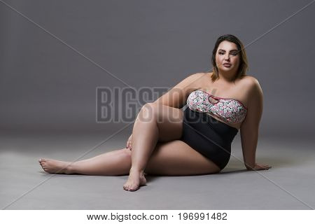 Plus size fashion model in sexy swimsuit young fat woman on gray studio background overweight female body full length portrait