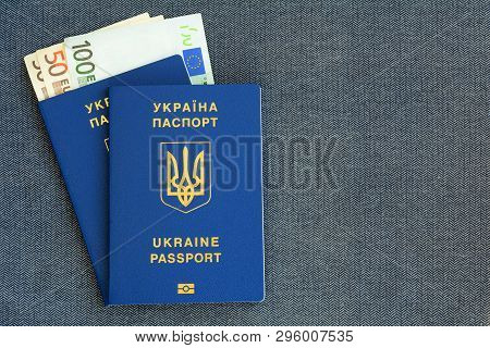 Two New Ukrainian Biometric Passport With Banknotes Euro On A Gray Cloth Herringbone Background.