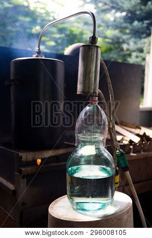 Moonshine Flows From A Homemade Moonshine Apparatus Into A Glass Jar. Production Of Moonshine In Rus