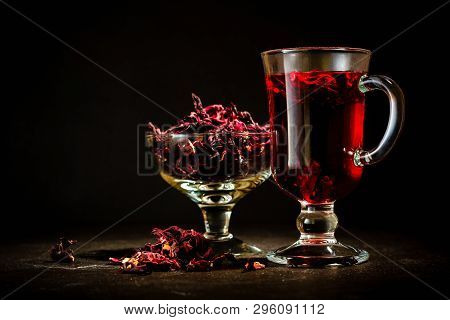 Transparent Glass Cup With Hot Red Tea From Hibiscus Or Hibiscus. Glassware And Dry Petals With Suga