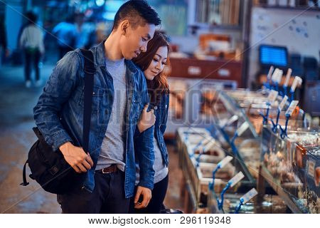 Romantic Asian Couple Looking For Something Special At Seafood Chainese Market. They Are Curious And