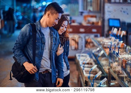 Romantic Asian Couple Looking For Something Special At Seafood Chainese Market. They Are Curious And