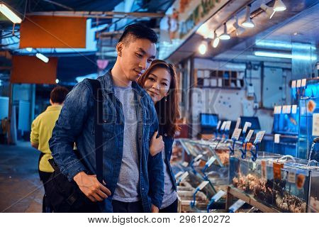 Happy Asian Couple Looking For Something Special At Chainese Market. They Are Pensive. A Lot Of Seaf