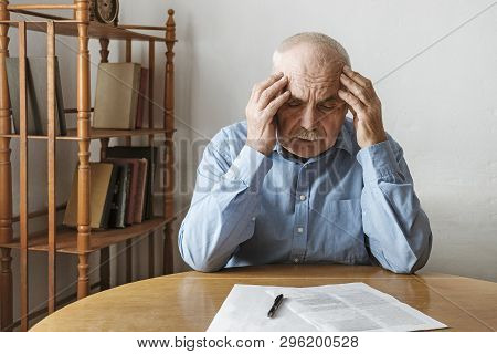 Depressed Worried Senior Man Looking At A Form On The Table In Front Of Him Awaiting His Signature R
