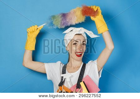 Young Girl With A Scarf On Her Head, Yellow Rubber Gloves Holds In Her Hands The Means For Cleaning 