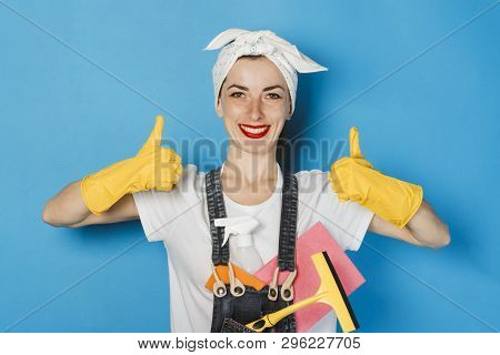 Young Girl With A Scarf On Her Head, Yellow Rubber Gloves And Cleaning Supplies Showing A Thumbs Up 