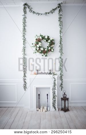 A Wreath Of Roses And Vines Hangs Above The Fireplace In The White Room. There Are Candles, A Decora