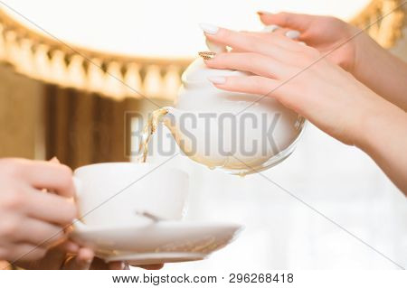 Tea Party. Women Pour Green Tea Into A White Cup