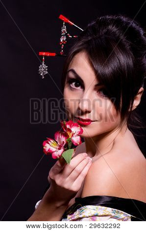 Beautiful young woman in Asian costume with red flowers