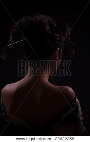 Beautiful young woman in Asian costume on black background.
