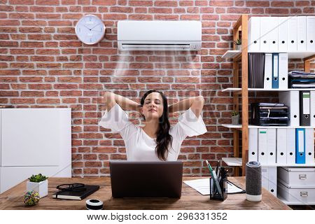 Relaxed Businesswoman Enjoying The Cooling Of Air Conditioner In The Office