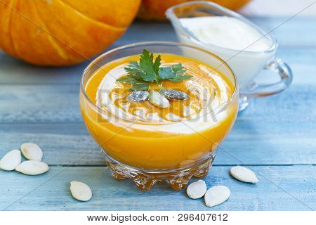 Home Made Pumpkin Cream Soup With Pumpkins And Parsley Leaves On Blue Wooden Table. Cream Soup Of Pu