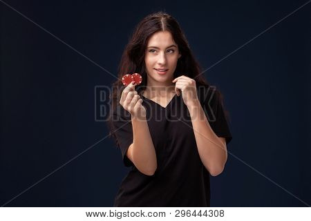 Curly Hair Brunette Is Posing With Red Gambling Chips In Her Hands. Poker Concept On A Black Backgro