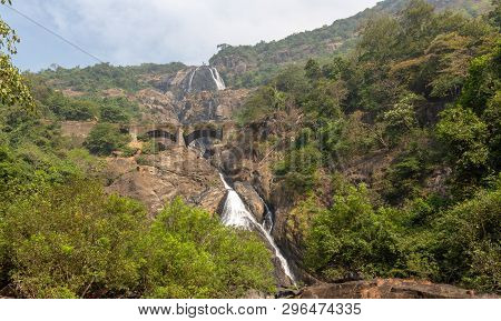 Railway Bridge Over The River Mandovi On The Background Of The Dudhsagar Waterfall