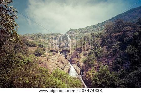 Railway Bridge Over The River Mandovi On The Background Of The Dudhsagar Waterfall