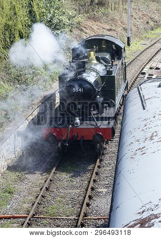 Old Steam Engine Backing Up On Tracks Showing Puffs Of Steam