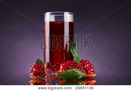 rijpe pomergranate en glas sap op paarse achtergrond