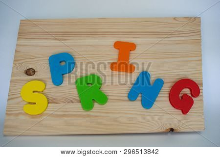 Multi-colored Letters Of The English Alphabet Laid Out The Word Spring On A Wooden Board Background