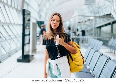 Teen girl waiting for international flight in airport departure terminal. Young passenger with backpack travelling on airplane. Teenager tourizm abroad alone concept.