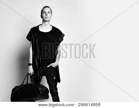 Young Stylish Man With A Bun On Head In T-shirt, Long Sleeveless Jacket And Worn Jeans With A Big Mo