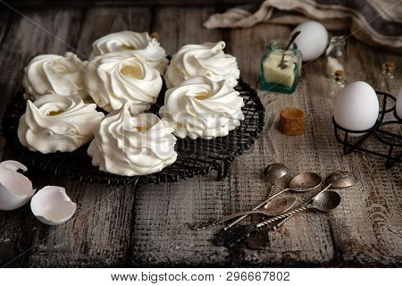 Homemade White Mini Meringue Desserts Pavlova On Wicker Metal Stand On Grey Wooden Table With Bottle