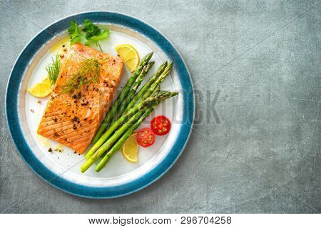 Grilled salmon steak garnished with green asparagus, lemon and tomatoes.Top view