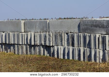 Row Of Gray Concrete Blocks In Dry Grass Outside