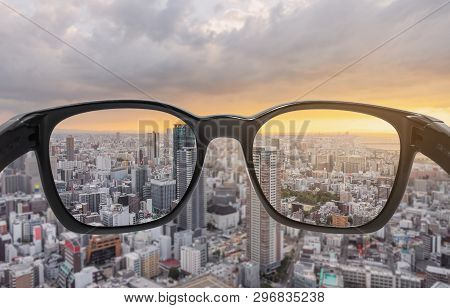 Looking Through Eyeglasses To City Sunset View, Focused On Lens With Blurry Background