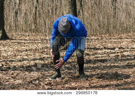 A Man In Training Clothes Injured The Periosteum While Jogging In Outdoor Workout. Concept Of Sports