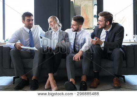Group Of Four Business People Sitting On Sofa. They Couldnt Be Happier About Working Together.