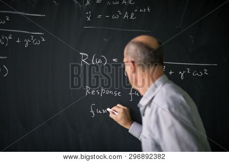Math teacher drawing   fuction graph on a blackboard during mathclass (shallow DOF, color toned image)