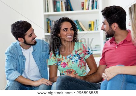 Latin American Man And Woman Talking With Group Of Friends Indoors At Home